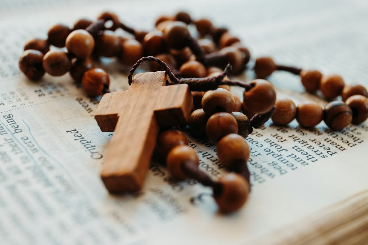 A wooden rosary resting on scripture